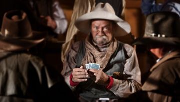 13791189 - bluffing card player in old american west saloon. hands in focus.